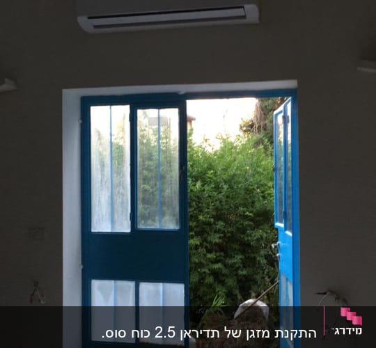 מזגן מותקן מעל דלתות כחולות פתוחות